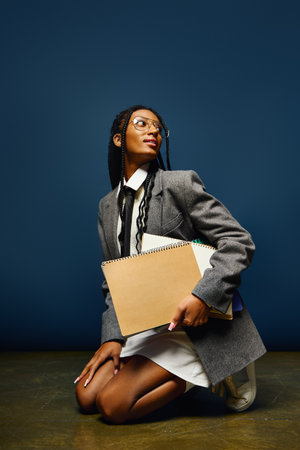A young woman kneels with a notebook, displaying her unique style and confidence.の写真素材