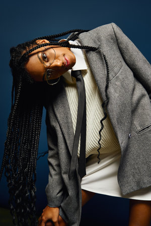 A young woman showcases her bold style, wearing a tailored outfit with a striking expression.の写真素材