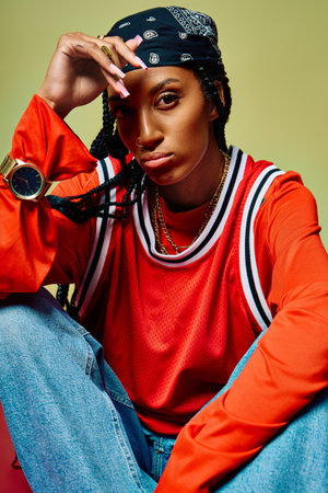 Stylish young woman sits comfortably, showcasing her unique fashion sense and attitude.の写真素材