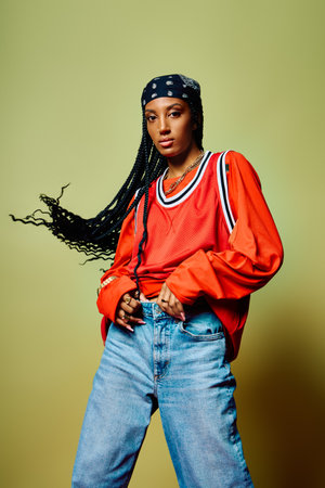 A young woman with braided hair showcases her stylish outfit while exuding confidence.