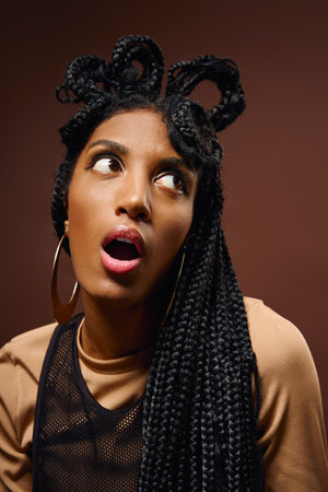 A young woman showcases a stunning, artistic hairstyle while displaying a playful expression.の写真素材