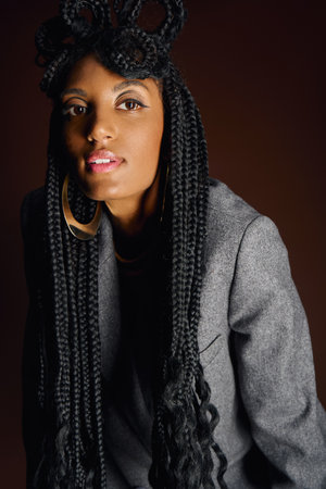 A young woman displays her stylish outfit and gorgeous braided hair in the studio.