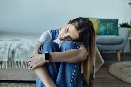 Pretty teenage girl sits comfortably on the floor, enjoying her personal space at home.の写真素材