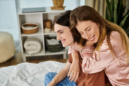 Two young individuals embrace happily in a relaxed indoor atmosphere, enjoying each others company.