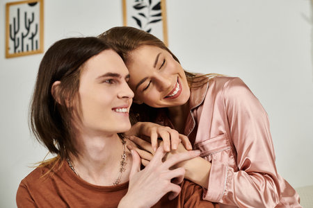 A young couple shares laughter and warmth in a chic indoor space with soft colors and modern decor.