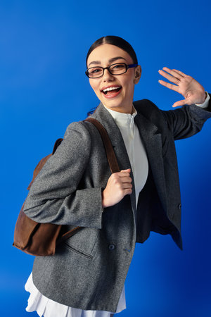 Emotional young woman with stylish attire excitedly greets the camera, showcasing her warm smile.の写真素材