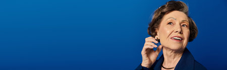 A beautiful mature woman elegantly poses in trendy attire, exuding confidence and charm, bannerの写真素材