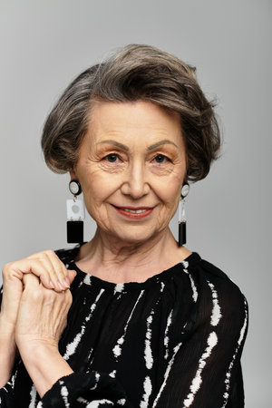 A beautiful woman in her 60s radiates elegance while posing gracefully in trendy attire.