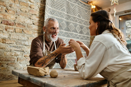 A beautiful couple enjoys quality time shaping clay during a pottery class, smiling and connecting.の写真素材