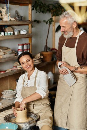 Mature couple shapes clay together in a pottery class, enjoying quality time and love.の写真素材