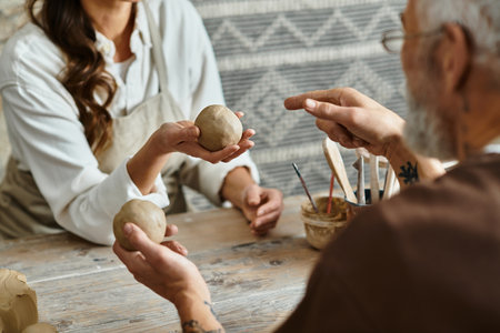 Beautiful mature couple enjoys quality time as they shape clay together in a pottery class.の写真素材