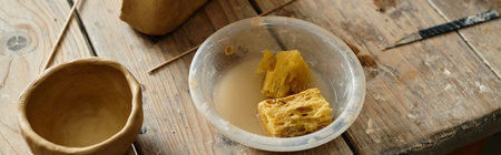 shaping clay near tools, sponges and finished pottery in an inviting studio space, bannerの写真素材