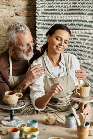 A beautiful mature couple shares a joyful moment shaping clay together during pottery class.