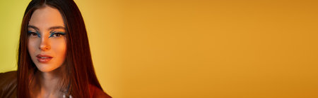 A beautiful young woman with captivating makeup poses in studio, banner