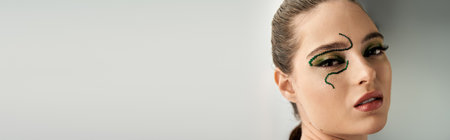A young woman showcases transformative snake makeup in a captivating studio setting, bannerの写真素材
