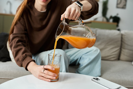 Bright and casual moment as a stylish young man pours juice in his cozy home.の写真素材