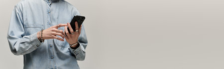 A handsome young man dressed in denim interacts with his smartphone, exuding confidence.