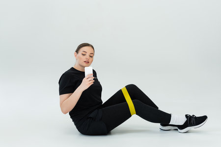 Female fitness enthusiast engages with her workout while seated, showcasing strength and style.