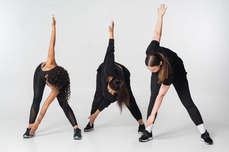 Three fit women stretch in stylish sportswear, promoting health and fitness together.の写真素材