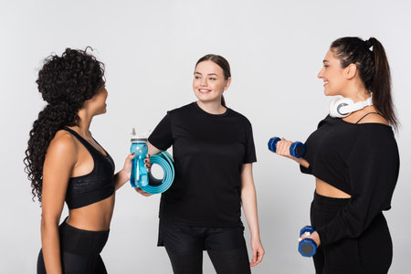 Three strong and fit women share motivation and laughter while working out together in a studio.