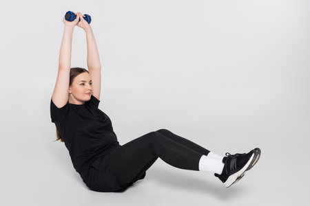Strong female athlete performs an overhead lift in a stylish and minimalistic workout space.
