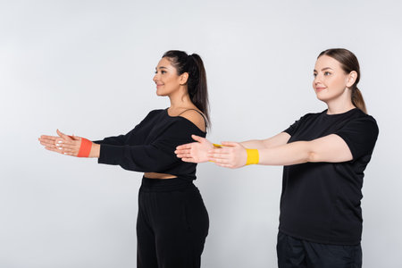 Two strong women in stylish sportswear showcase strength through dynamic exercises together.の写真素材