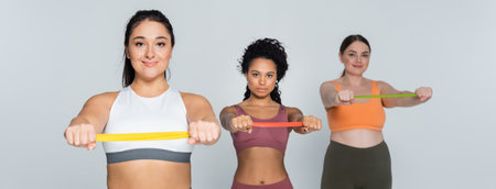 Three determined female athletes focus on strengthening their bodies with resistance bands.