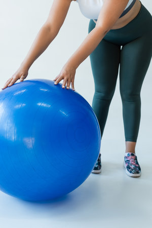 Strong and fit woman exercises with a blue stability ball during a workout session in a studio.の写真素材