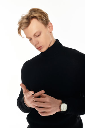 A young man in a stylish black turtleneck stands thoughtfully, exuding elegance.の写真素材