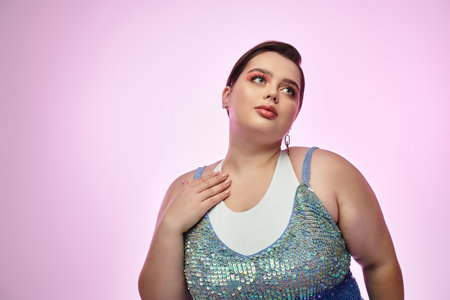 Plus size woman showcases her beauty with confidence, dressed in shimmering outfit under pink light.のeditorial素材