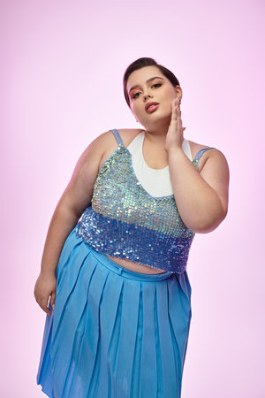 A young plus size woman poses gracefully, showcasing her stunning outfit against a pastel backdrop.のeditorial素材