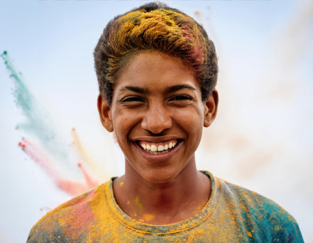 A young boy beams with joy, covered in vibrant powders during the Holi festival.の素材