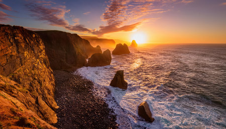 Golden sunset casts warm hues over rocky coastline during summer evening.の素材