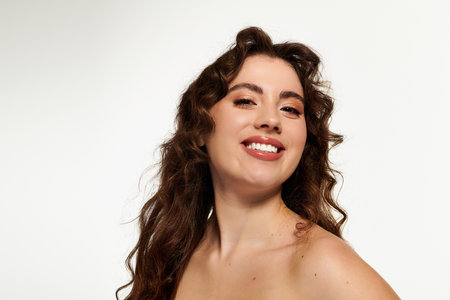 A young woman with curly hair smiles brightly, exuding confidence and style in soft light.のeditorial素材