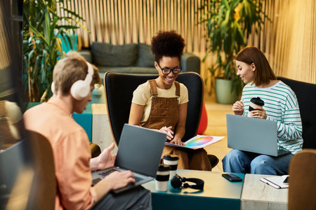 Group of colleagues engaged in discussion and work at a hotel lounge area, sharing ideas.のeditorial素材