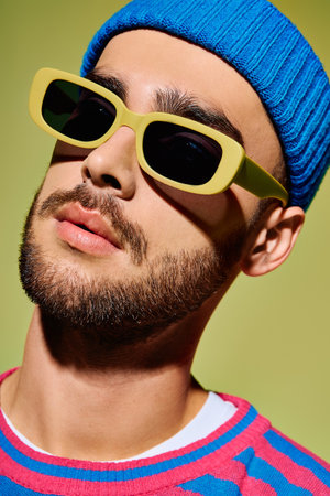 A young man exudes confidence in a stylish outfit and trendy sunglasses against a green backdrop.の写真素材