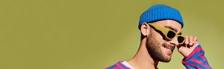 Handsome young man in trendy outfit smiles confidently while wearing fashionable sunglasses, banner