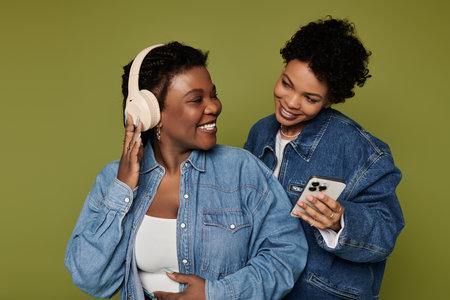 Two beautiful women in fashionable attire enjoy each others company while listening to music.の写真素材