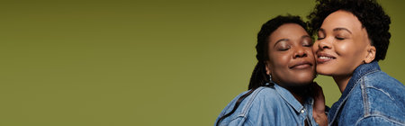 Two loving women in trendy outfits display their affection in a chic and stylish setting.の写真素材