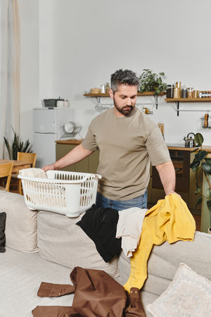 A man sorts through freshly cleaned laundry in a cozy home, surrounded by a warm, inviting decor.の写真素材