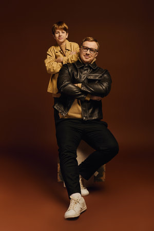 A father and son share a cheerful moment, showcasing their fashionable casual wear together.