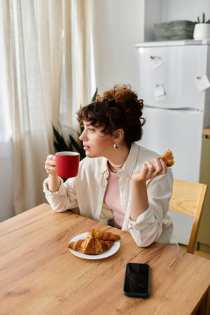 Young woman savors her coffee while relaxing at a wooden table with delicious pastries.のeditorial素材