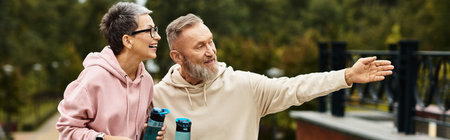 A mature couple shares laughter while walking in a lush park, embracing their joyful moment.の写真素材