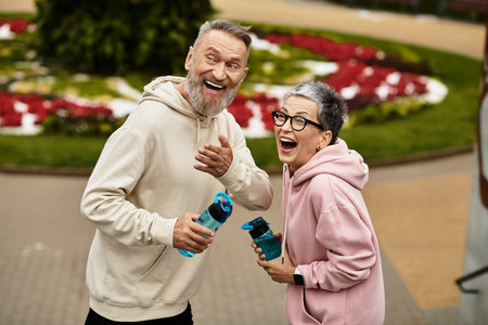 A mature couple enjoys a lighthearted walk in a beautifully landscaped park, sharing laughter.の写真素材