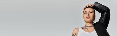 Confident young woman poses with attitude, showcasing her unique style and artistic tattoos.のeditorial素材