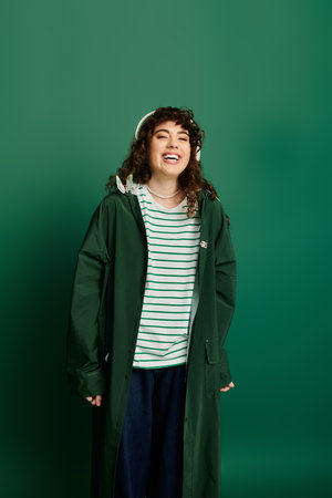 A young woman radiates happiness while wearing a fashionable outfit in a lively green setting.の写真素材