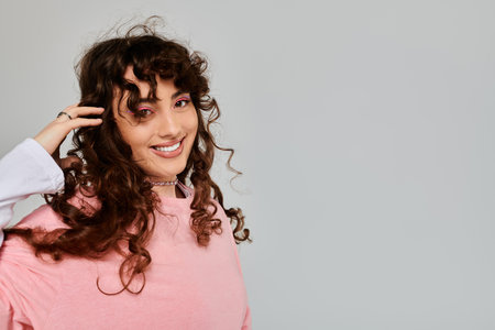A young woman with curly hair highlights her trendy style and joy against a neutral background.