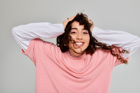A fashionable woman radiates happiness while playfully posing with hands in her hair.の写真素材