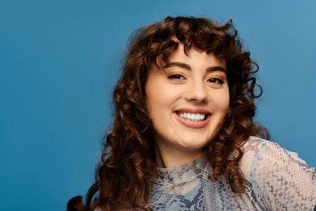 Young woman with curly hair displays happiness while dressed in trendy attire, radiating confidence.