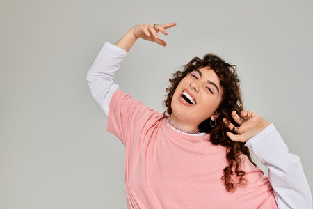 A fashionable woman showcases her playful spirit with a bright smile while posing creatively.